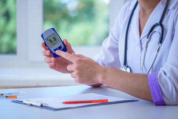 Doctor shows glucose meter with blood glucose level to diabetes patient during medical consultation and examination in hospital. Diabetic lifestyle and healthcare
