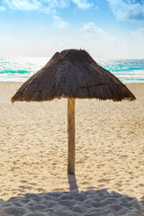 Empty beach with one thatched sun umbrella