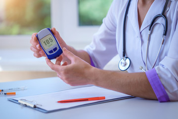 Doctor shows glucose meter with blood glucose level to diabetes patient during medical consultation...