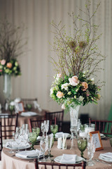 Beautiful composition with flowers on the tables and candles for guests at a wedding or a birthday party