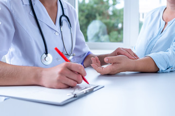 Professional general medical doctor measuring pulse of patient and write the diagnosis and treatment of the disease during a medical examination and consultation in hospital