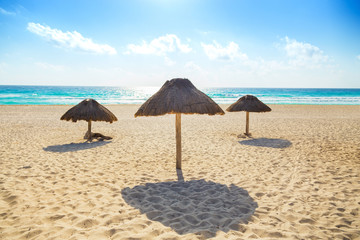 Empty beach with three thatched sun umbrellas