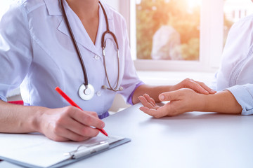 Medical doctor measuring pulse of patient and write the diagnosis and treatment of the disease...