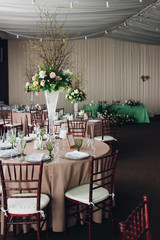 Beautiful composition with flowers on the tables and candles for guests at a wedding or a birthday party