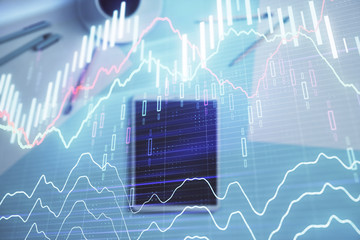 Double exposure of forex graph on digital tablet laying on table background. Concept of market analysis