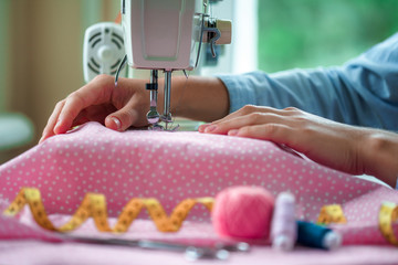 Seamstress sews clothes using a sewing machine. Tailoring process using sewing accessories