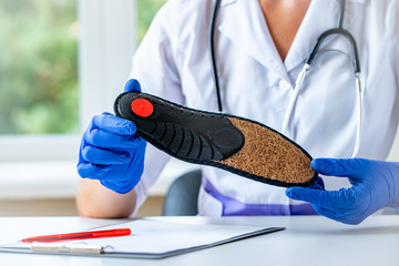 Doctor holds orthopedic insoles for the treatment and prevention of flat feet. Foot care