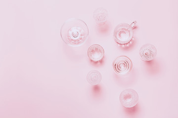 Many empty glasses on pink background. Top view, flat lay.