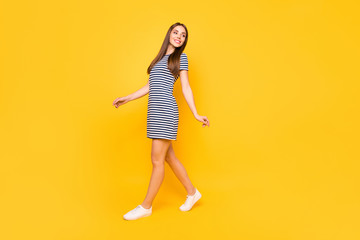 Fototapeta na wymiar Full body photo of nice girl glad walking favorite park with friends wear striped white blue dress isolated yellow background