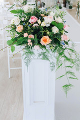 Indoor wedding ceremony with white wedding arch decorated with flowers and big white candles