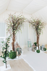 Indoor wedding ceremony with white wedding arch decorated with flowers and big white candles