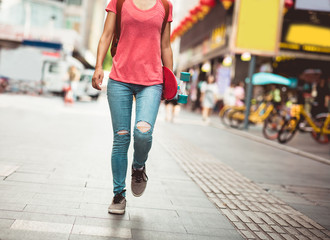 Woman walking with skateboard in hand at city