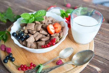 Breakfast dried chocolate pads on dark wooden background. Healthy tasty breakfast chocolate square pads with strawberries, raspberries, black currants and red currants.