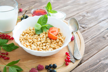 Breakfast cereal on a rustic wood background, overhead view Healthy tasty breakfast of muesli with strawberries, raspberries, black currants and red currants.