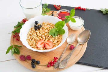 Fresh granola, muesli with yogurt and berries on marble background. Healthy tasty breakfast of muesli with strawberries, raspberries, black currants and red currants.