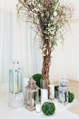 Indoor wedding ceremony with white wedding arch decorated with flowers and big white candles