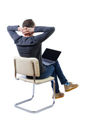 Back view of a man who sits on a chair with a laptop.