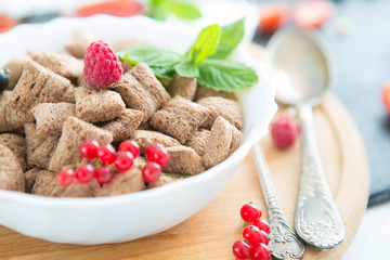 healthy breakfast cereal with fruit on the summer table with a white tablecloth Healthy tasty breakfast chocolate square pads with strawberries, raspberries, black currants and red currants.