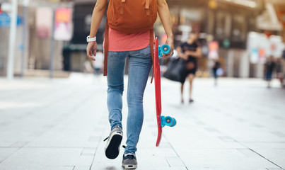 Woman skateboarder walking with skateboard in hand at city © lzf