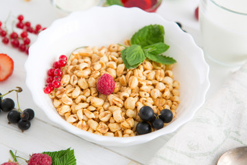 Healthy breakfast with corn flakes, berries, waffle and milk on blue background. Close up. Healthy tasty breakfast of muesli with strawberries, raspberries, black currants and red currants.