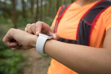 Asian woman ultramarathon runner set the sports watch before running at tropical rainforest trail