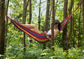 Relaxing in hammock,using smartphone in tropical rainforest