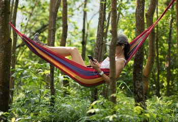Obraz na płótnie Canvas Relaxing in hammock,using smartphone in tropical rainforest