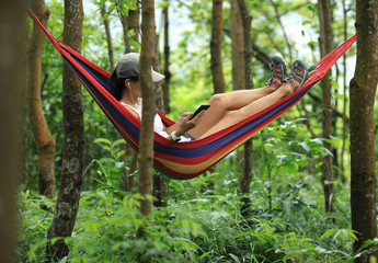 Obraz na płótnie Canvas Relaxing in hammock with smartphone in tropical rainforest