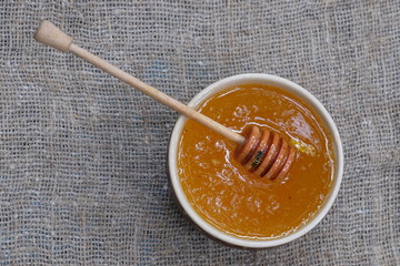 organic honey in bowl, wooden honey deeper on natural background, healthy lifestyle, apiculture, healthy products and food, beekeeping, hive honey harvesting