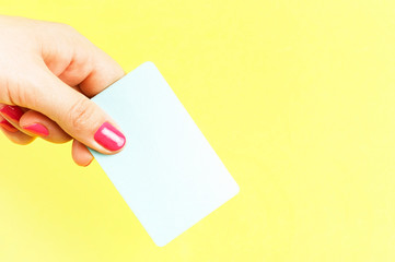 Obraz premium Female hand holds a bank card close-up on a yellow background