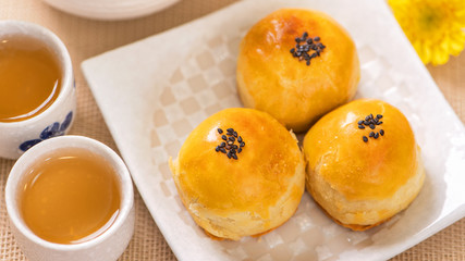 Tasty baked egg yolk pastry moon cake for Mid-Autumn Festival on bright wooden table background. Chinese festive food concept, close up, copy space.