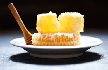 Fresh honey healthy food yellow sweet honeycomb slice with wooden dipper on white plate