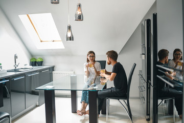 Obraz premium Young couple drinking their coffees at home in the kitchen. Morning time in the kitchen