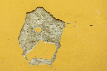 Loch im Putz, Putz mit Farbe abgefallen und teilweise gerissen, Hauswand verschmutzt und verschmiert mit Textfreiraum als Hintergrund