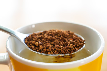 Spoon of Instant coffee granules pour in cup of coffee, White background, Close up & Macro shot, Selective focus, Relax time, Drink concept