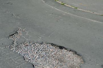 Poor condition of the road surface. Summer season. Hole in the asphalt, risk of movement by car,...