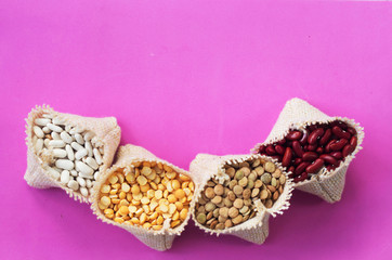 Soy kidney beans and peas in small bags on pink background copy space