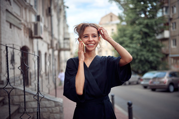 Fototapeta premium Elegant woman in a black dress talking on the phone