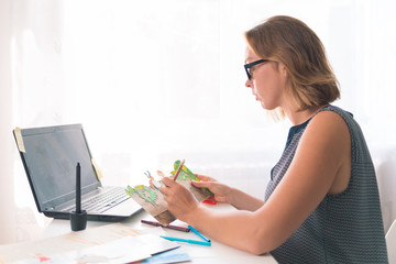 Teacher or speech therapist at work. Young woman with glasses sitting at the table and working with materials for children. Nearby are a laptop and office supplies. Close up