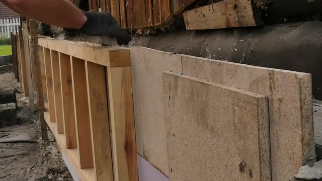 worker dismantles the wooden formwork, new foundation for old house. 4K