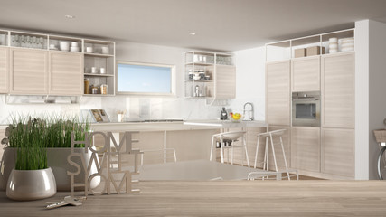 Wooden table, desk or shelf with potted grass plant, house keys and 3D letters making the words home sweet home, over modern white kitchen, interior design, blur background
