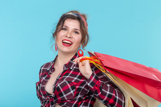 Happy young beautiful woman in a plaid shirt and jeans and holding a bag on a blue background. Concept of shopping and buying new products.