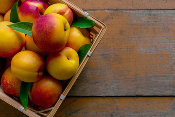 Nectarines with leaves on a wooden background. Summer fruits. Food photo. View from above.