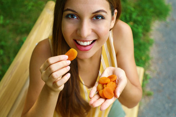 Close up view from above of a woman eating dried apricots outdoors. Healthy food concept.