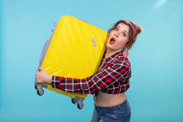 Frightened young beautiful woman in vintage clothes holding a yellow suitcase in her hands posing...