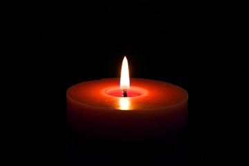 Single candle red flame isolated on black with selective focus