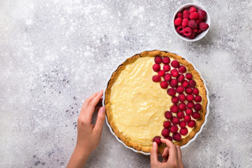 Cooking the cake. Baking with raspberries. Preparation for the tart. Hands of the young woman put summer berry.