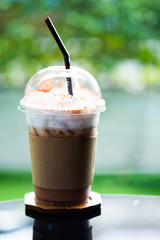 Glass of iced coffee mocha with chocolate powder and milk foam