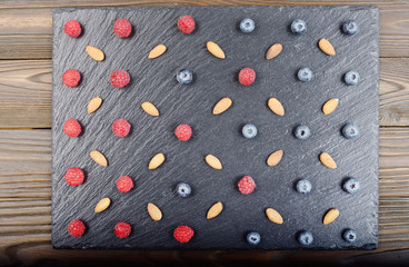 Flat lay view at ripe bilberry raspberry and almond on slate stone tray closeup