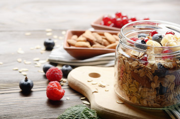 Fruit healthy muesli in glass jar on kitchen wooden table